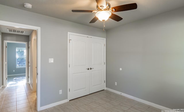 unfurnished bedroom with ceiling fan, light tile patterned floors, and a closet