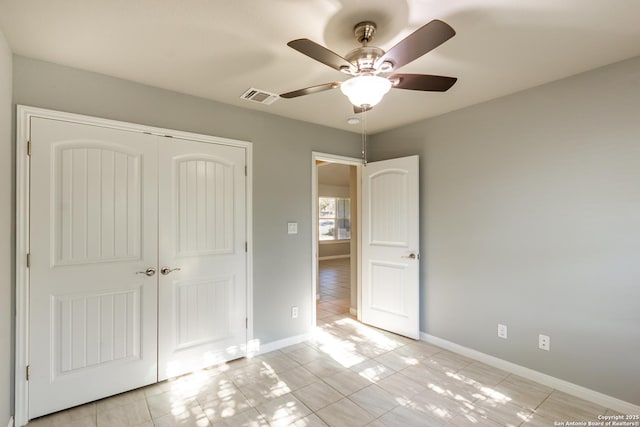 unfurnished bedroom with ceiling fan, light tile patterned floors, and a closet