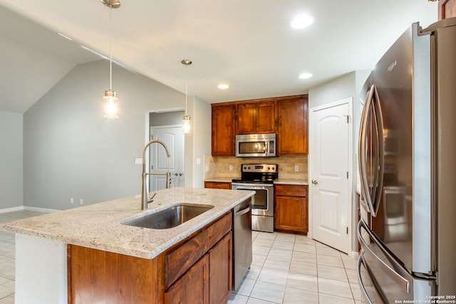 kitchen featuring a center island with sink, stainless steel appliances, tasteful backsplash, pendant lighting, and sink