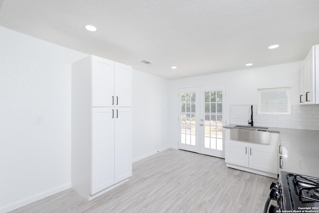 kitchen with french doors, gas stove, white cabinets, and tasteful backsplash