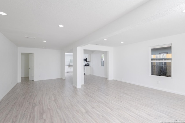 unfurnished room featuring a textured ceiling and light hardwood / wood-style flooring