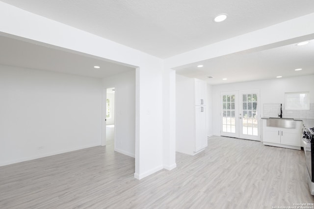 unfurnished living room with light hardwood / wood-style floors, french doors, and sink