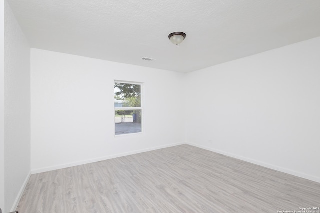 unfurnished room with light wood-type flooring and a textured ceiling