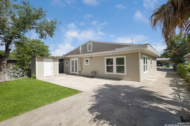 view of front of house featuring french doors, an outdoor structure, a patio, and a front yard