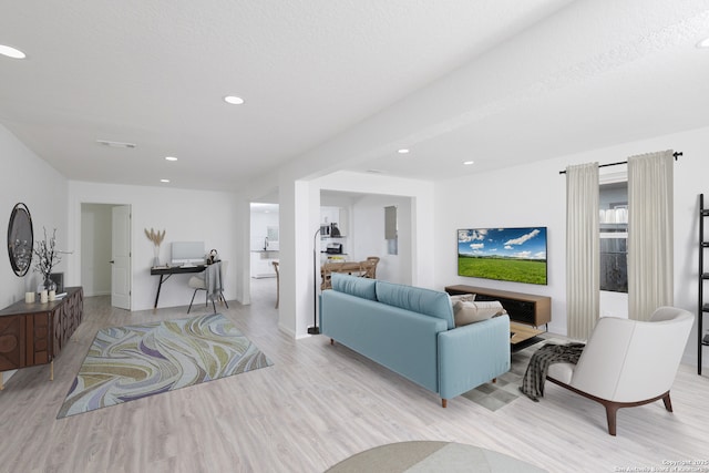 living room featuring light wood-type flooring and a textured ceiling