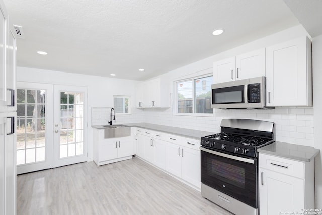 kitchen with tasteful backsplash, appliances with stainless steel finishes, sink, and white cabinetry