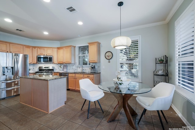 kitchen featuring stainless steel appliances, sink, light brown cabinetry, and decorative light fixtures