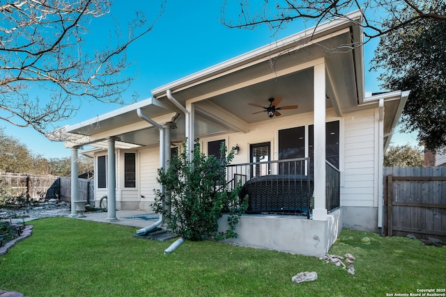 back of property with ceiling fan and a yard