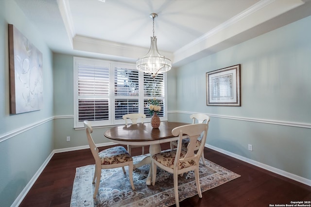 dining room featuring dark hardwood / wood-style flooring, crown molding, a raised ceiling, and a chandelier