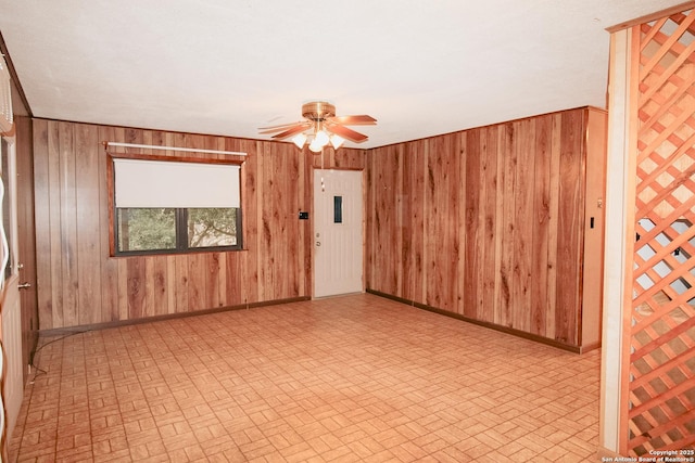 unfurnished room with ceiling fan and wood walls