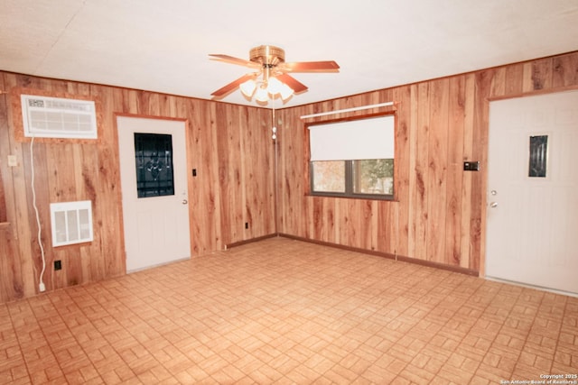 spare room featuring wooden walls, ceiling fan, and an AC wall unit