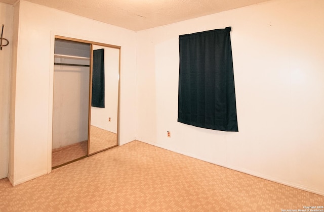 unfurnished bedroom with a textured ceiling, a closet, and carpet