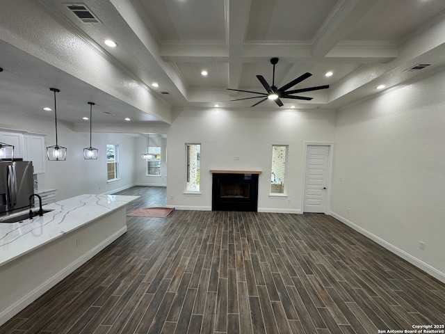 unfurnished living room with coffered ceiling, sink, beamed ceiling, ceiling fan, and ornamental molding