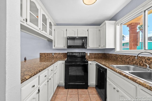 kitchen featuring white cabinetry, light tile patterned flooring, dark stone countertops, black appliances, and sink