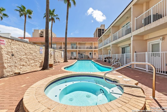 view of swimming pool with a hot tub and a patio