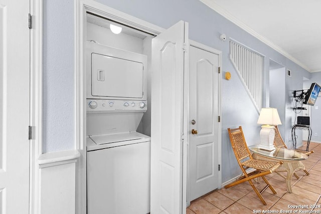 laundry room with light tile patterned flooring, stacked washer / dryer, and ornamental molding