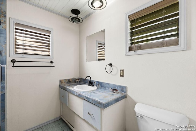 bathroom featuring tile patterned floors, toilet, vanity, and a healthy amount of sunlight