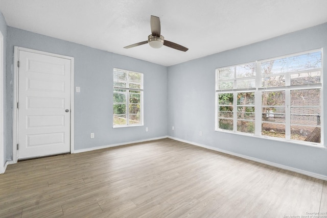 empty room with ceiling fan, plenty of natural light, and wood-type flooring