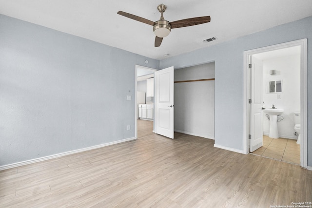 unfurnished bedroom with ensuite bath, ceiling fan, a closet, and light hardwood / wood-style floors