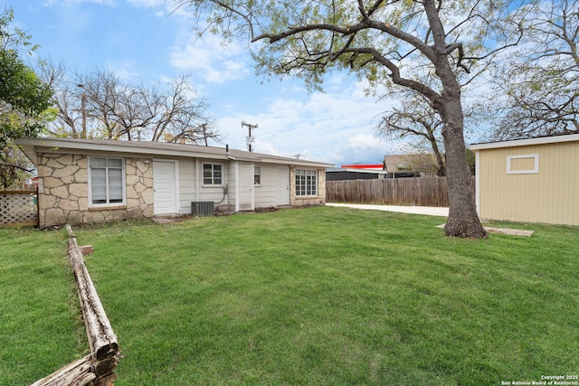 back of house featuring central air condition unit and a yard