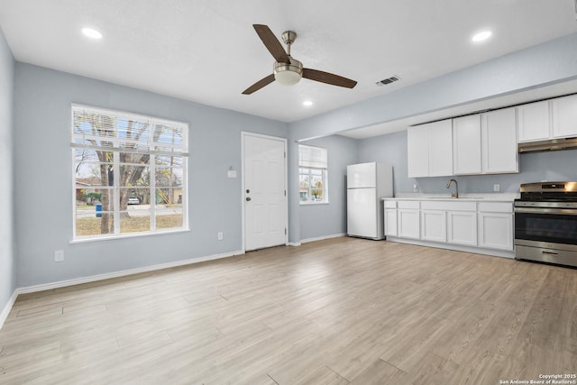 kitchen featuring white fridge, sink, light wood-type flooring, stainless steel range, and white cabinets