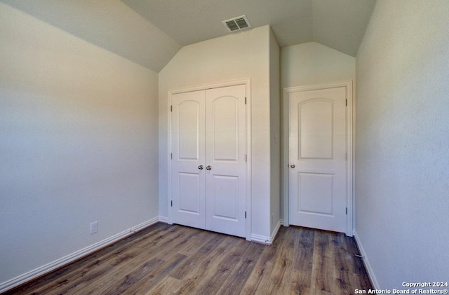 unfurnished bedroom with a closet, vaulted ceiling, and dark hardwood / wood-style floors