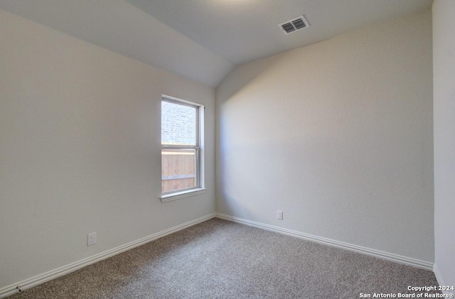 carpeted empty room with lofted ceiling