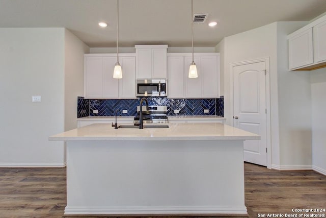 kitchen with white cabinets, decorative light fixtures, stainless steel appliances, sink, and a center island with sink