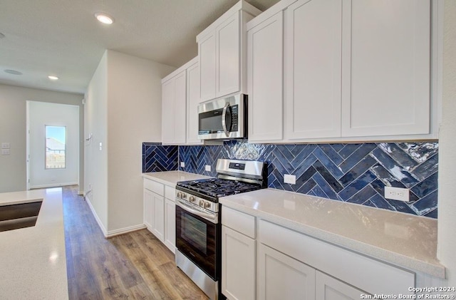 kitchen featuring tasteful backsplash, appliances with stainless steel finishes, white cabinetry, and light hardwood / wood-style floors