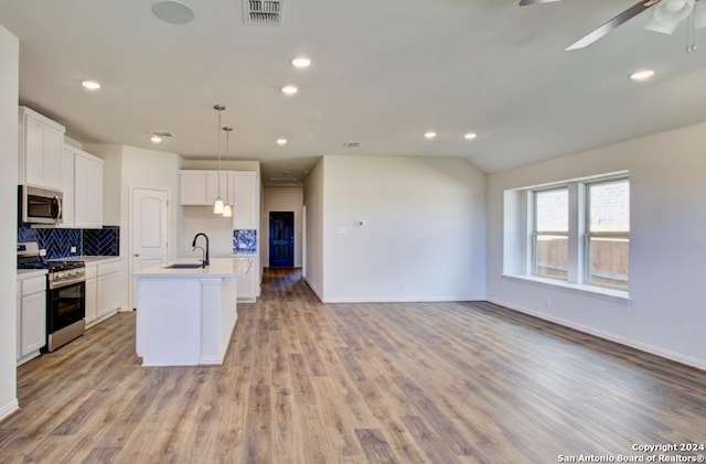 kitchen with hanging light fixtures, sink, stainless steel appliances, and white cabinetry