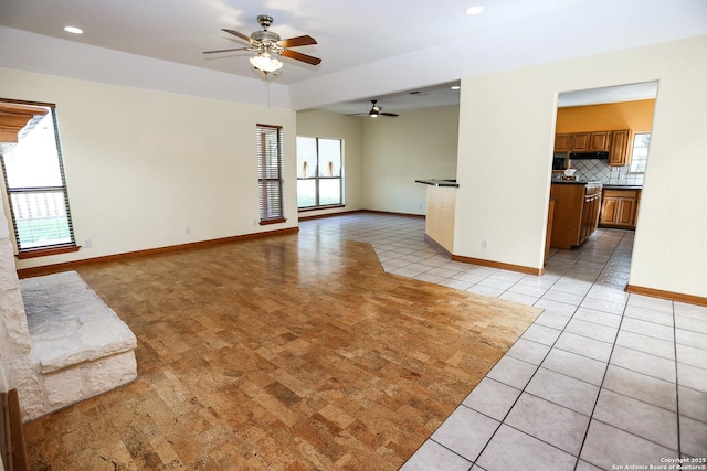 unfurnished living room with light tile patterned flooring, a wealth of natural light, and ceiling fan