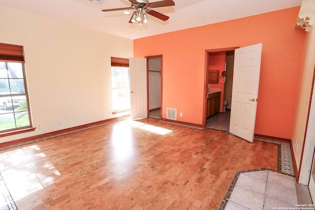 unfurnished bedroom with ensuite bathroom, light wood-type flooring, and ceiling fan