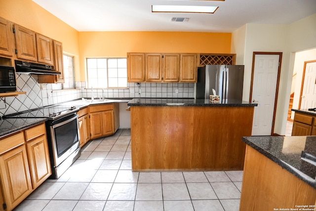 kitchen with sink, a center island, light tile patterned floors, dark stone countertops, and stainless steel appliances