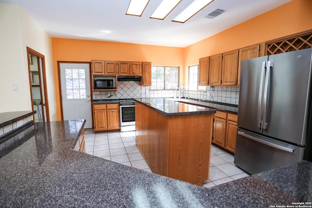 kitchen featuring tasteful backsplash, appliances with stainless steel finishes, a center island, and light tile patterned floors