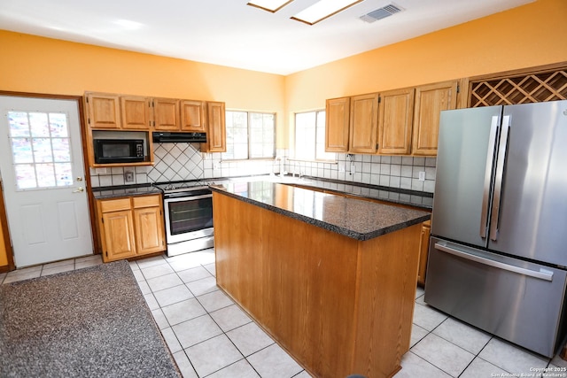 kitchen with tasteful backsplash, a healthy amount of sunlight, appliances with stainless steel finishes, and a kitchen island