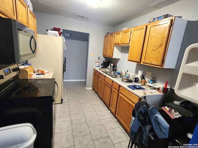 kitchen with a textured ceiling, stainless steel range with electric cooktop, light tile patterned flooring, and sink