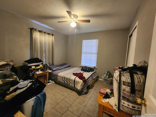 bedroom with ceiling fan, light tile patterned floors, and a textured ceiling