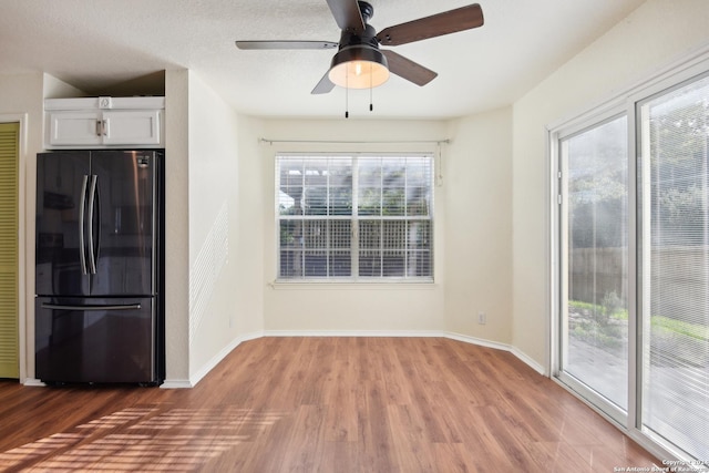 kitchen with wood-type flooring, white cabinetry, fridge, and ceiling fan