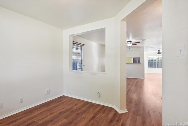 unfurnished room with plenty of natural light, dark wood-type flooring, and ceiling fan