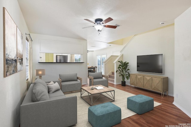 living room featuring wood-type flooring, a textured ceiling, and ceiling fan