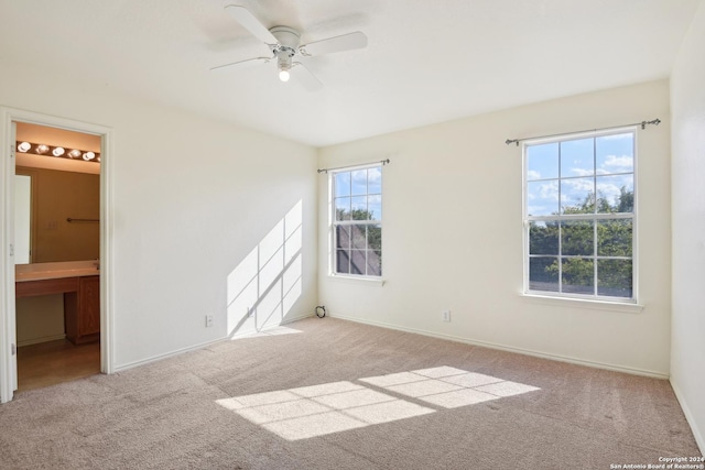 unfurnished room featuring ceiling fan, a wealth of natural light, and light carpet