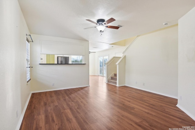 unfurnished living room featuring ceiling fan, dark wood-type flooring, and a textured ceiling