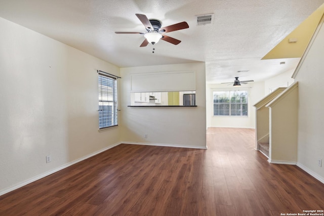 unfurnished living room featuring a textured ceiling, dark hardwood / wood-style floors, and ceiling fan