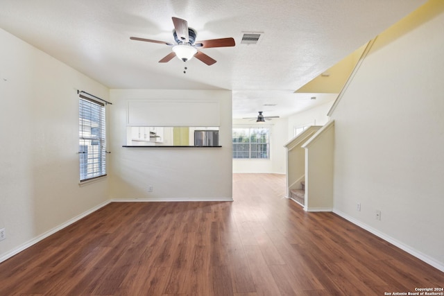 unfurnished living room with ceiling fan, dark hardwood / wood-style floors, and a textured ceiling