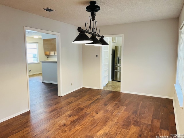 unfurnished dining area featuring dark hardwood / wood-style floors and a textured ceiling