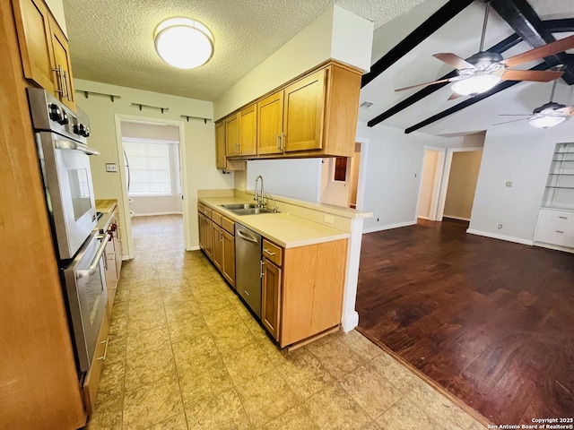 kitchen with ceiling fan, kitchen peninsula, sink, appliances with stainless steel finishes, and a textured ceiling