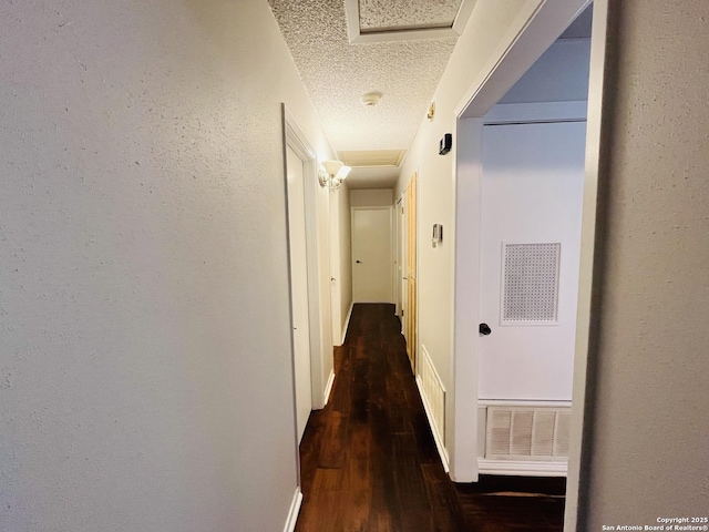 hallway with a textured ceiling and dark wood-type flooring