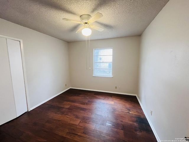 empty room featuring ceiling fan, dark wood-type flooring, and a textured ceiling