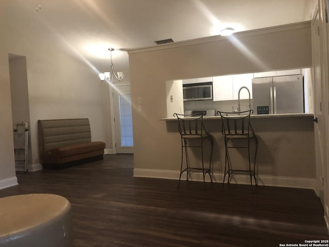 kitchen with decorative light fixtures, kitchen peninsula, appliances with stainless steel finishes, a kitchen breakfast bar, and white cabinets