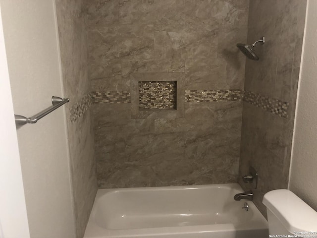 bathroom with toilet and tiled shower / bath combo